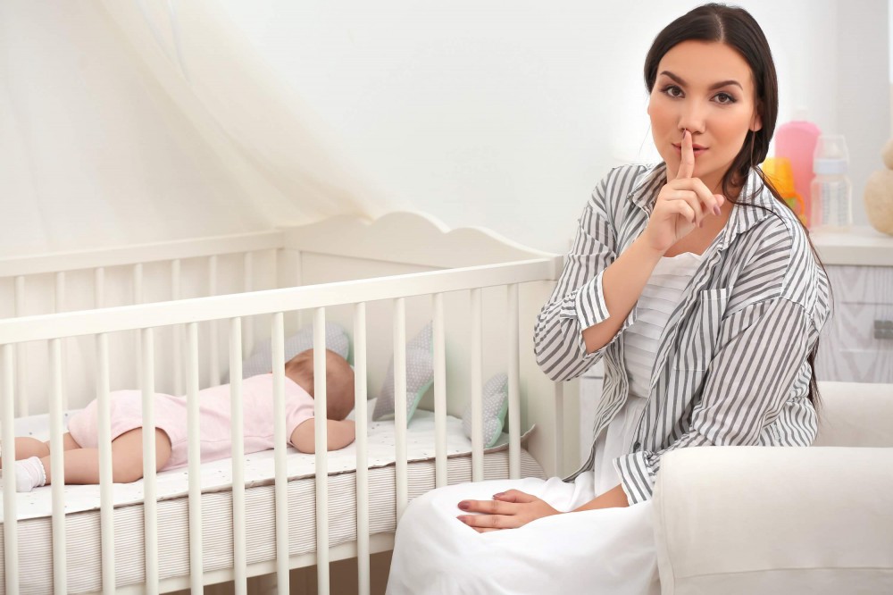 Mutter sitzt am Bett eines kleinen Kindes